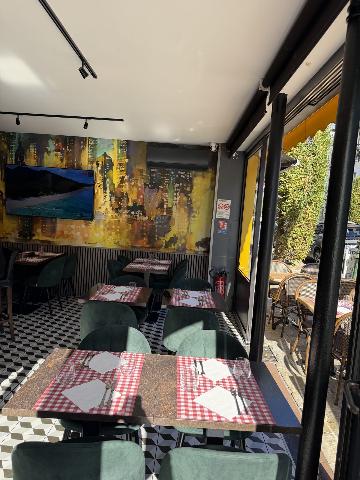 La salle du Cosy, ses tables dressées et sa grande fresque murale